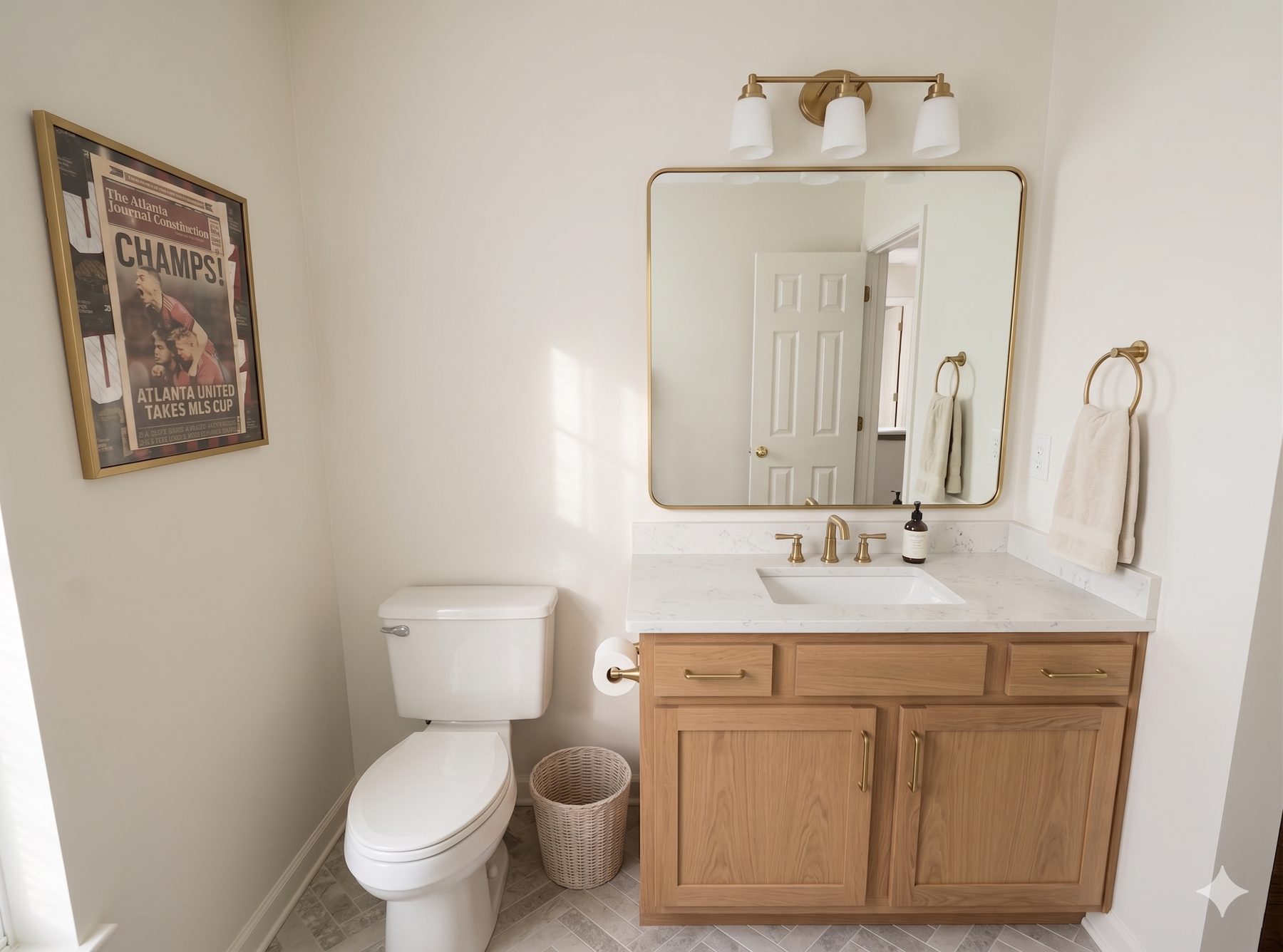 Lisa & Alex bathroom — design render of new oak vanity, white quartz, brass mirror and sconces with framed Atlanta United print