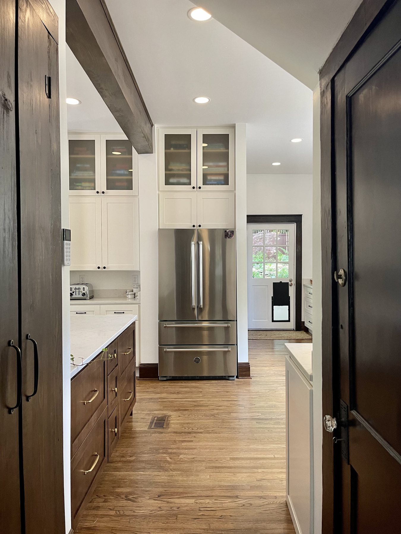 Birmingham kitchen — finished view to island, beam, glass-front uppers, and stainless range