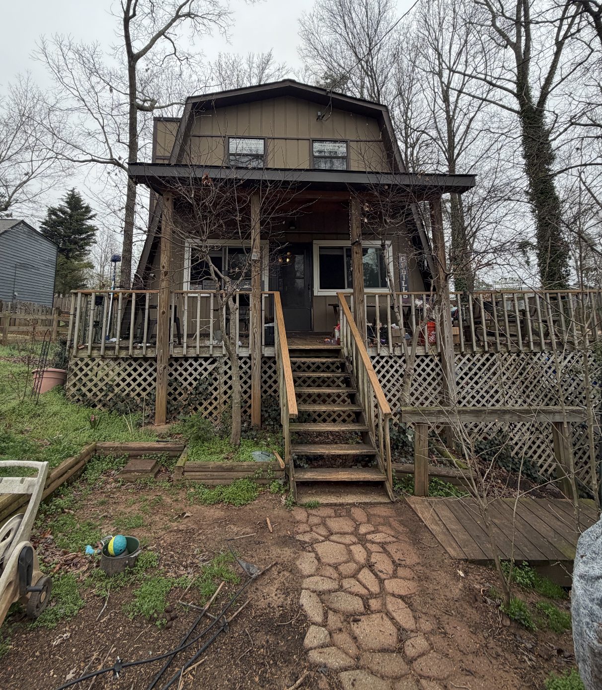 Lanier Lake House — before photo, dark cedar gambrel with weathered wood deck